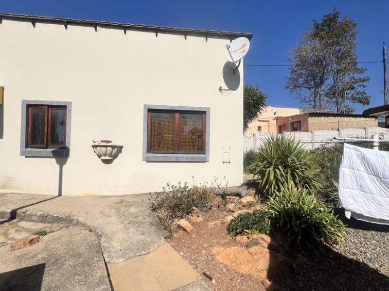 Rear exterior view of the cottage featuring a paved patio area, wall-mounted fountain, and satellite dish installation.