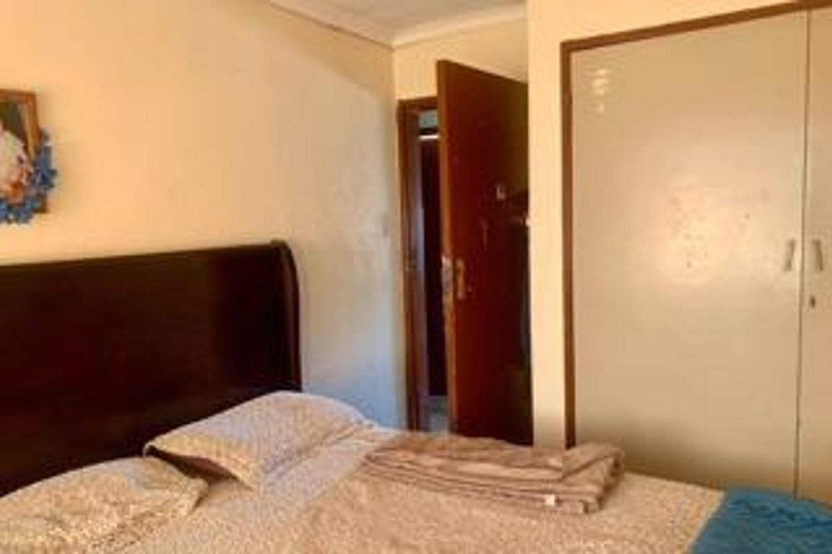 A bedroom featuring built-in wardrobe cabinetry and a standard interior door, showing signs of wear and dated finishes.