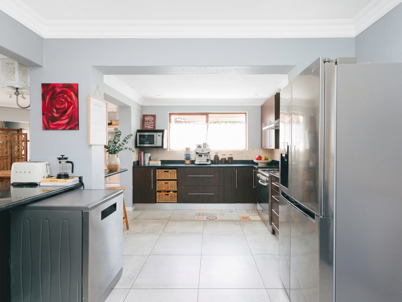 Modern kitchen featuring dark wood cabinetry, granite countertops, stainless steel appliances, and tiled flooring, offering a functional and well-maintained cooking space.