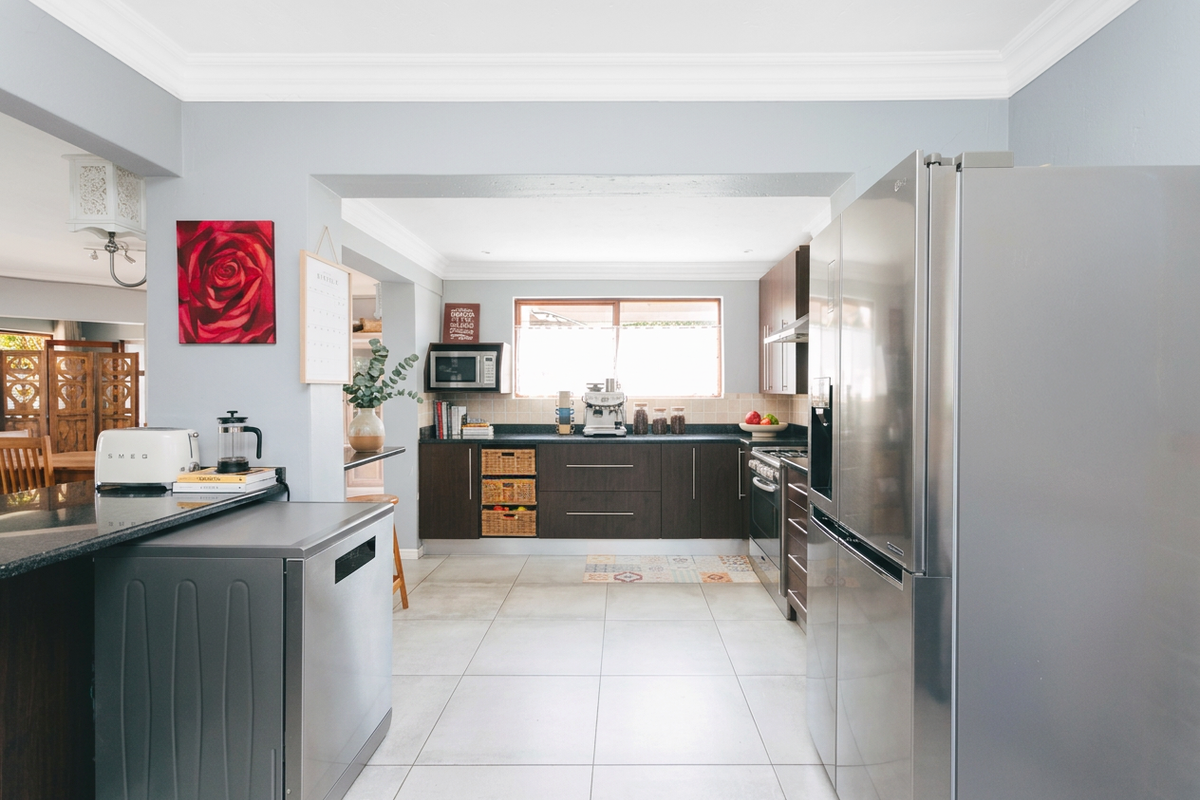 Modern kitchen featuring dark wood cabinetry, granite countertops, stainless steel appliances, and tiled flooring, offering a functional and well-maintained cooking space.