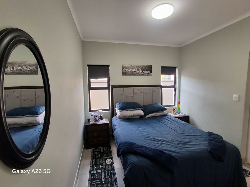 A well-maintained bedroom featuring tiled flooring, neutral wall tones, and dual windows with roller blinds, providing a clean and functional living space.