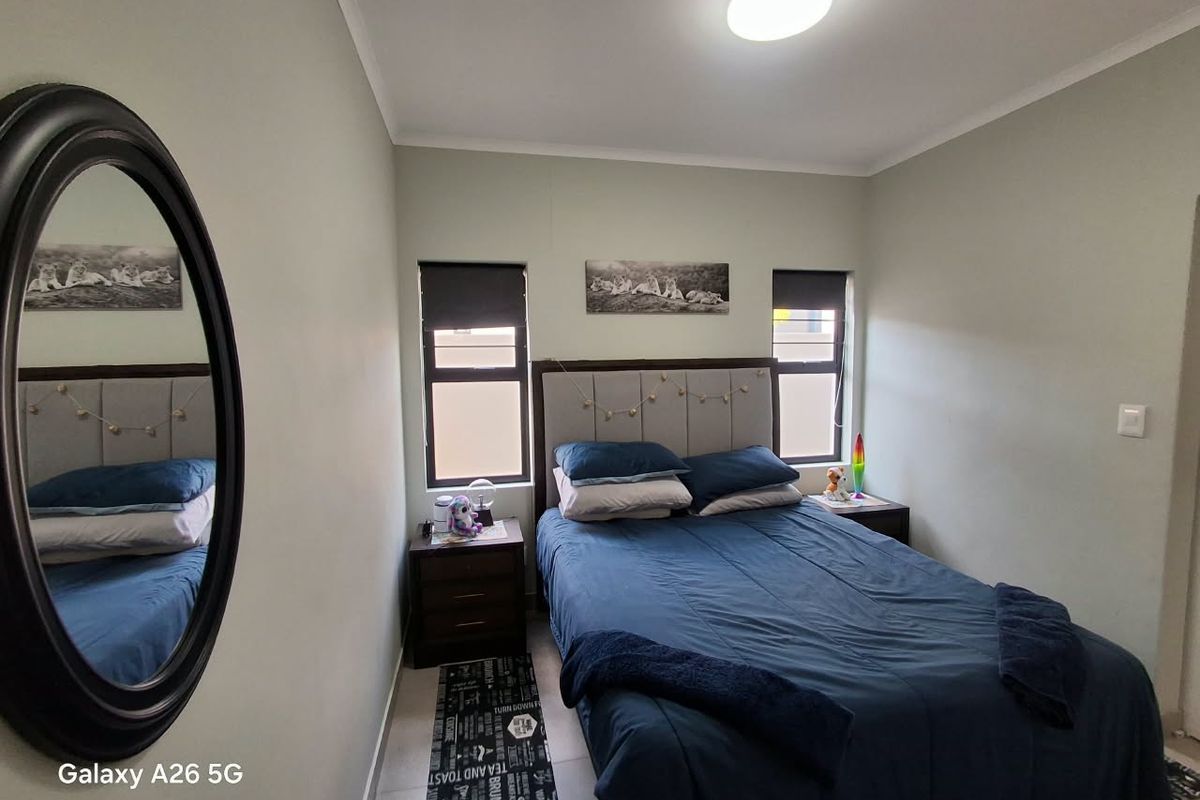 A well-maintained bedroom featuring tiled flooring, neutral wall tones, and dual windows with roller blinds, providing a clean and functional living space.