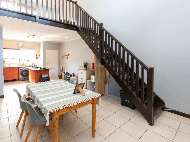 Open plan living and dining area featuring a staircase leading to a mezzanine level and an integrated kitchen with cabinetry.