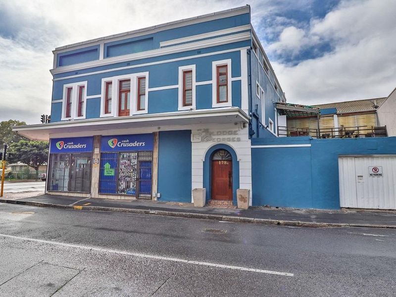 Street-facing view of a multi-level commercial and residential building featuring a blue facade, ground-floor retail space, and a private entrance.