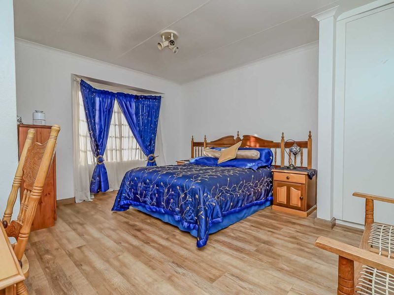 A bedroom featuring laminate flooring, built-in cupboards, and a ceiling-mounted spotlight fixture.