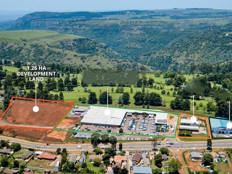 Aerial view of a commercial property complex featuring a 1.26-hectare vacant development plot, existing commercial buildings, and paved parking facilities.