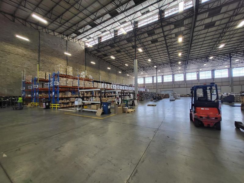 Spacious industrial warehouse featuring high ceilings, exposed steel trusses, concrete flooring, and extensive built-in pallet racking systems for efficient storage and logistics operations.