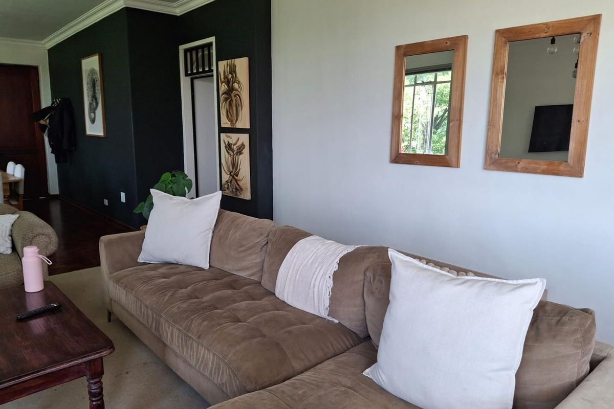 A living room area featuring a dark accent wall, crown molding, and neutral flooring, providing a comfortable space for relaxation.