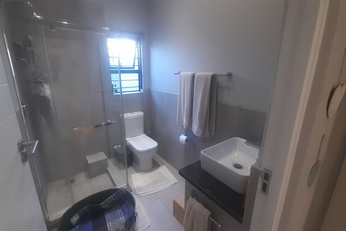 A modern bathroom featuring a glass-enclosed shower, a contemporary vessel sink on a vanity, and a toilet.