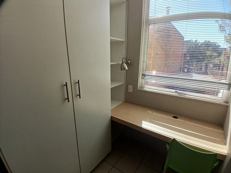 A functional home office space featuring a built-in desk, integrated shelving, and a large wardrobe, providing ample storage and workspace.