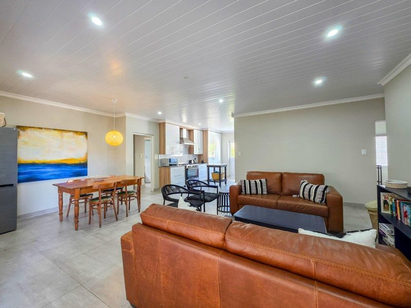 Spacious open-plan living and dining area featuring tiled floors, recessed lighting, and a modern kitchen with built-in cabinetry and appliances.