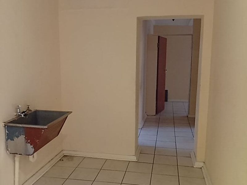 A functional laundry area featuring a wall-mounted utility sink and tiled flooring, providing a practical space for household tasks.
