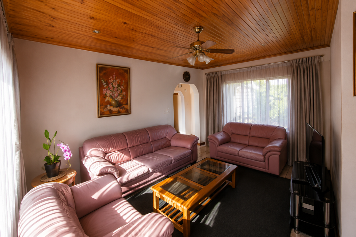 A comfortable living room featuring a warm timber tongue and groove ceiling, a central ceiling fan, and a classic arched doorway.