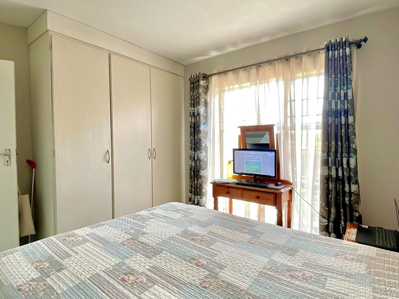 A functional bedroom featuring built-in cupboards and a sliding door providing natural light and access to the exterior.