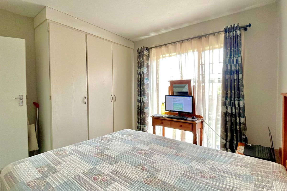 A functional bedroom featuring built-in cupboards and a sliding door providing natural light and access to the exterior.