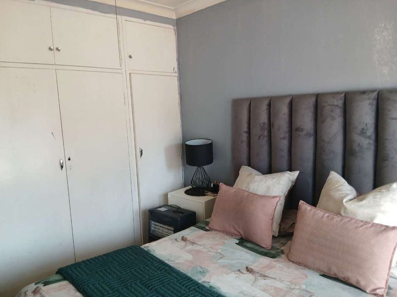 A bedroom featuring built-in cupboards and grey painted walls, offering a functional space with potential for cosmetic updates.