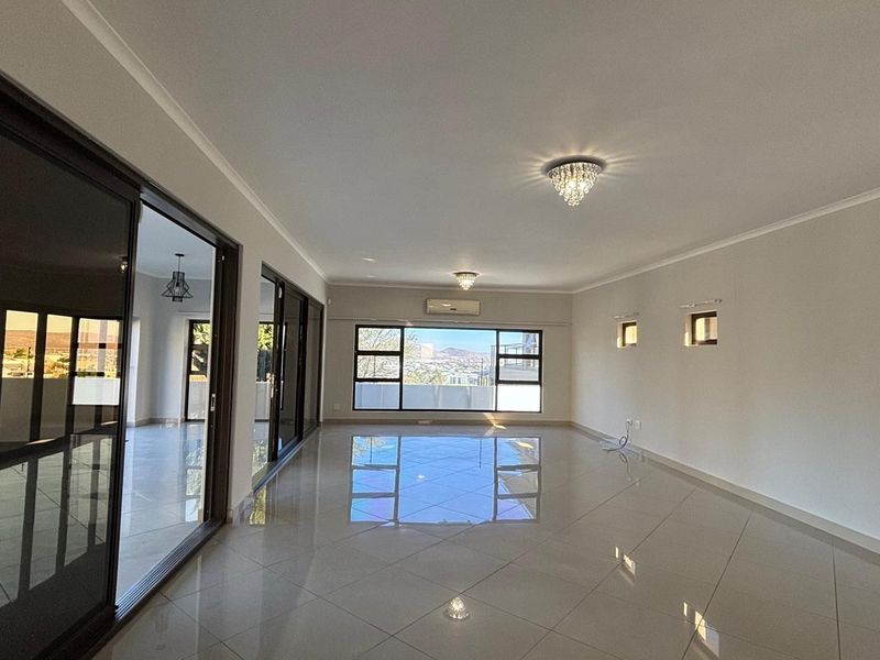Spacious, light-filled living area featuring polished porcelain tiles, elegant crystal chandeliers, and large sliding doors opening to a scenic view.