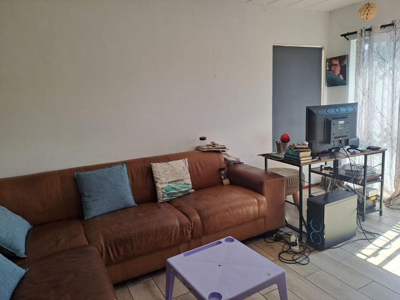 A living room area featuring tiled flooring and a sliding glass door, providing access to natural light.
