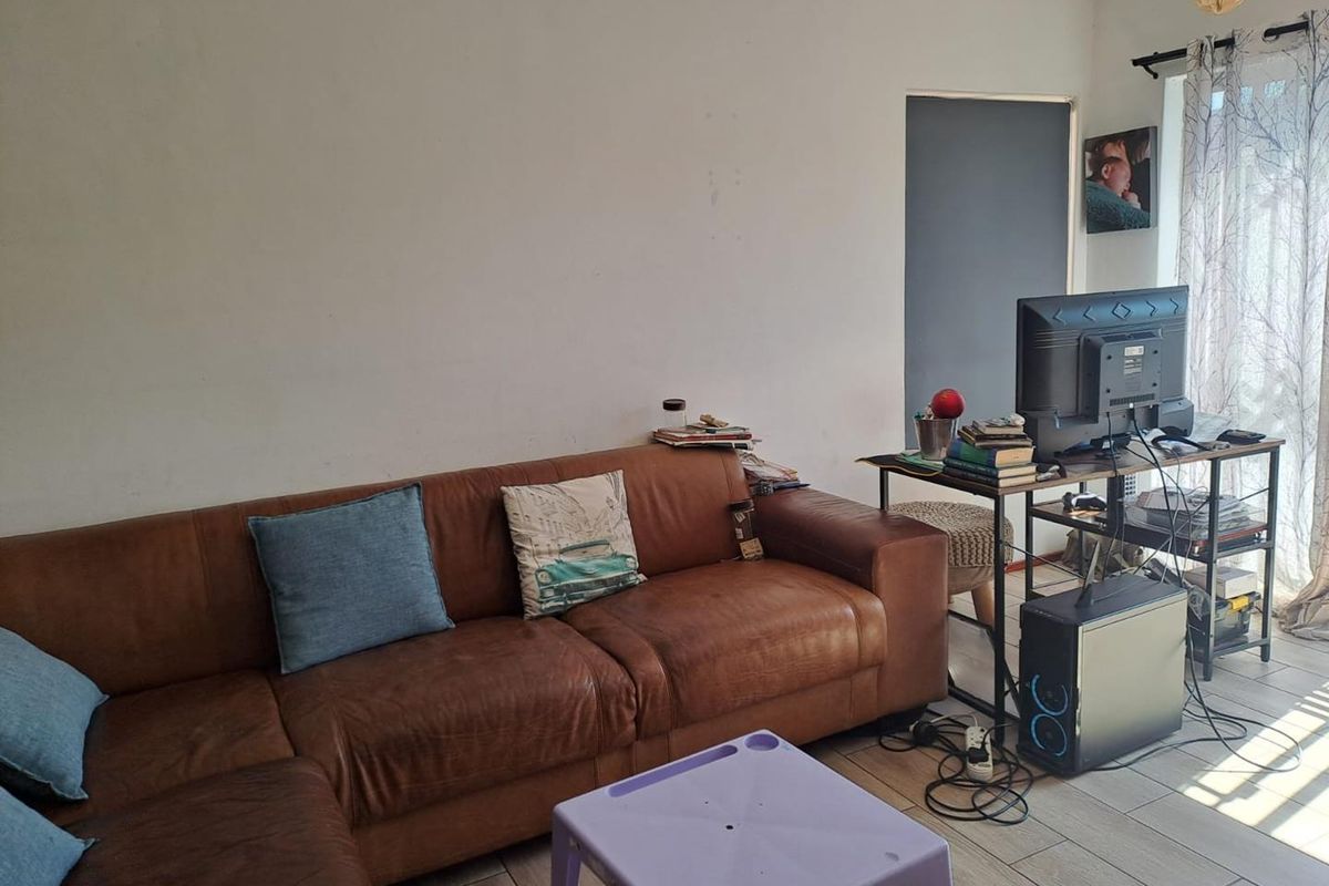 A living room area featuring tiled flooring and a sliding glass door, providing access to natural light.