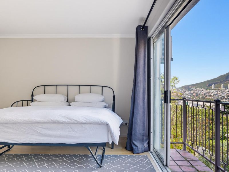 Bright bedroom featuring sliding glass doors that open onto a private balcony with scenic mountain and neighborhood views.