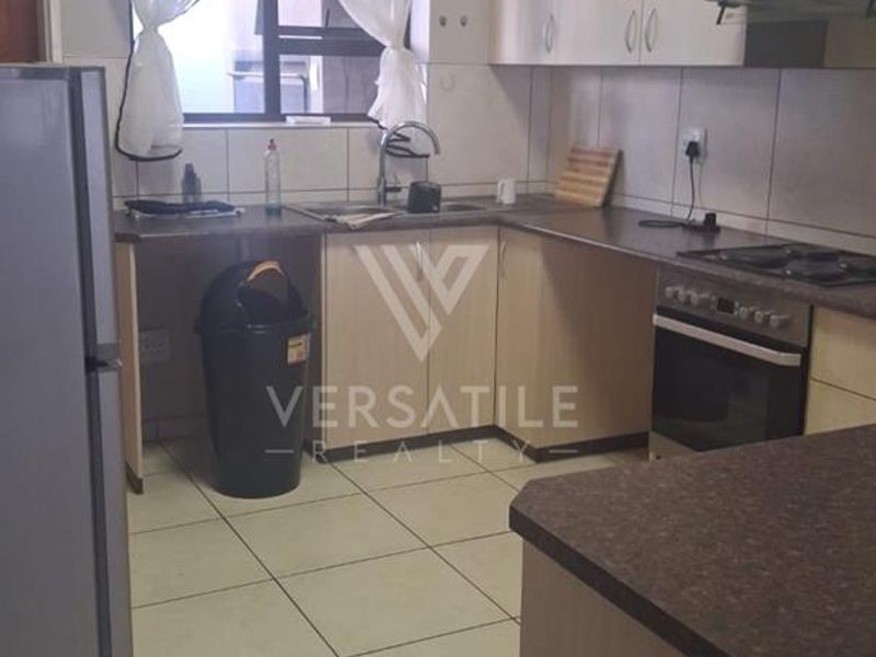 A functional kitchen featuring laminate cabinetry, tiled backsplash, built-in oven, hob, and extractor fan with tiled flooring throughout.