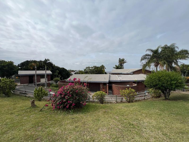 A wide-angle view of the property exterior featuring a brick facade, tiled roof, and a paved driveway set within a landscaped garden.