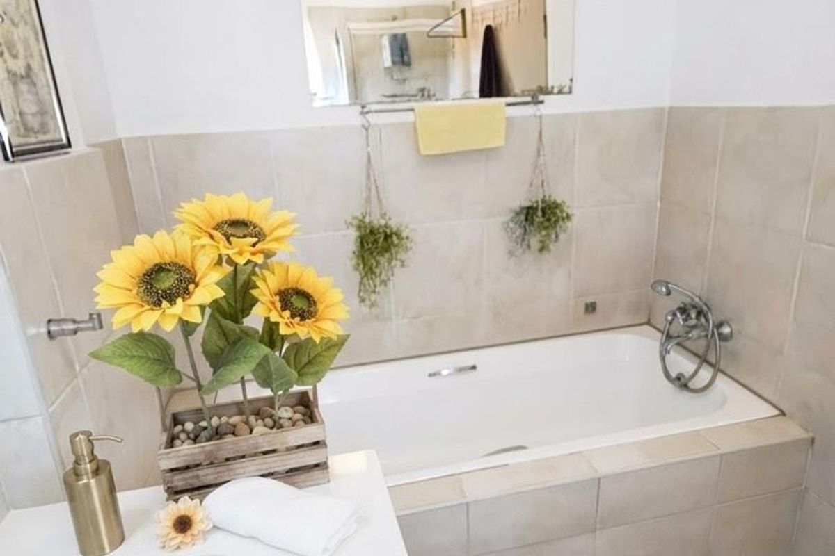 A functional bathroom featuring a built-in bathtub with tiled surround, a vanity basin, and neutral ceramic floor tiling.