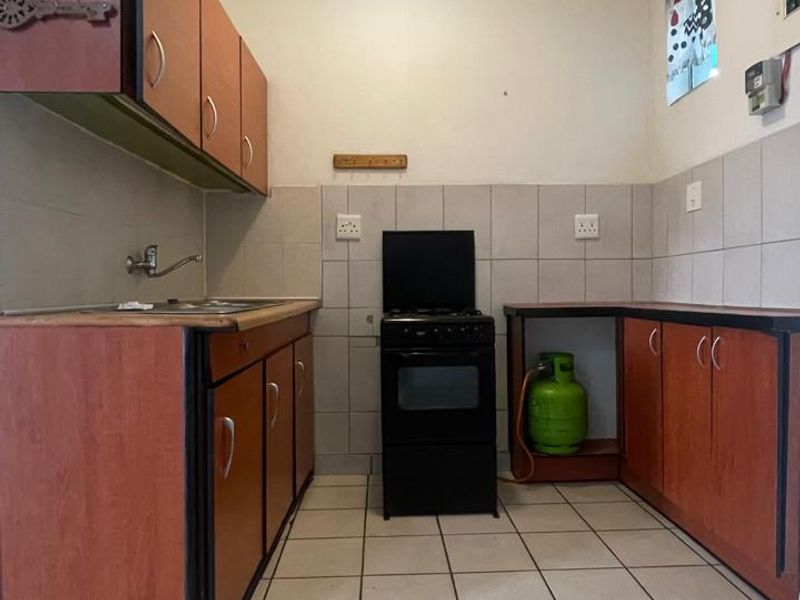 A functional kitchen featuring laminate cabinetry, tiled splashbacks, tiled flooring, and a gas stove setup.