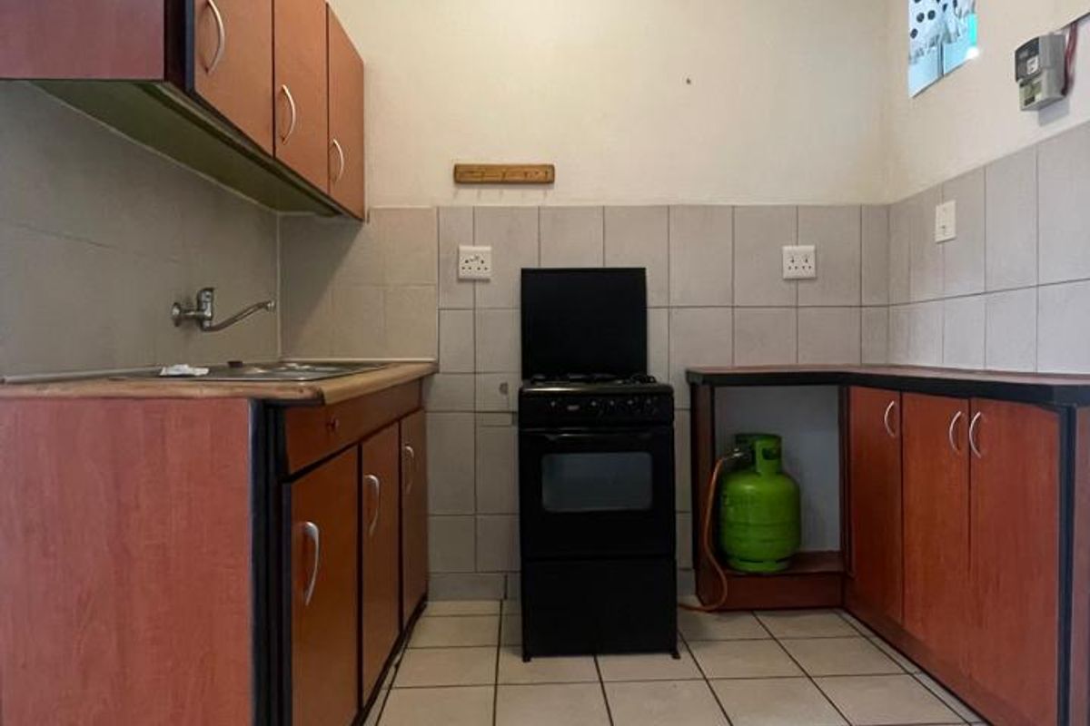 A functional kitchen featuring laminate cabinetry, tiled splashbacks, tiled flooring, and a gas stove setup.