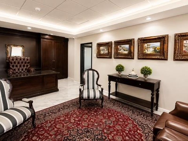 A professional office space featuring high-end built-in cabinetry, elegant marble flooring, and sophisticated recessed ceiling lighting.