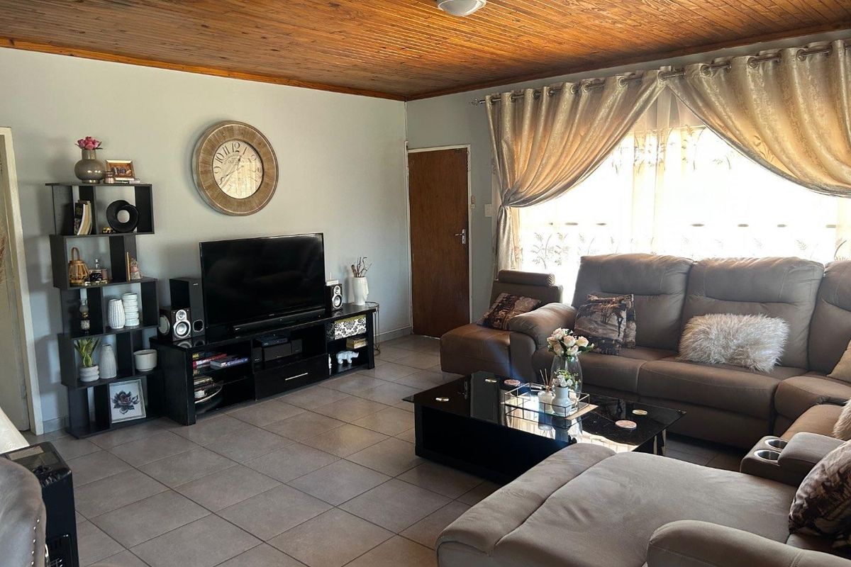 A spacious living room featuring tiled flooring and a distinctive timber-paneled ceiling, providing a warm and inviting atmosphere for relaxation.