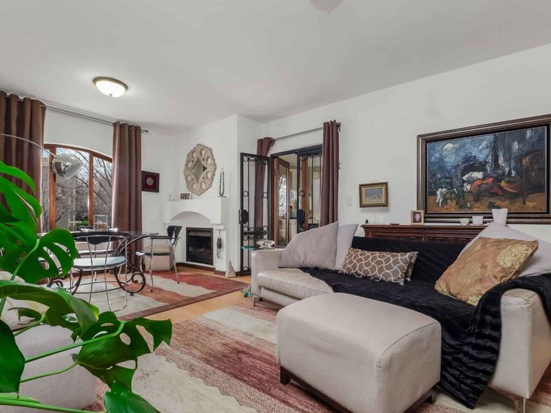 Spacious living room featuring a fireplace, arched window, and access to an outdoor area through security-gated french doors.
