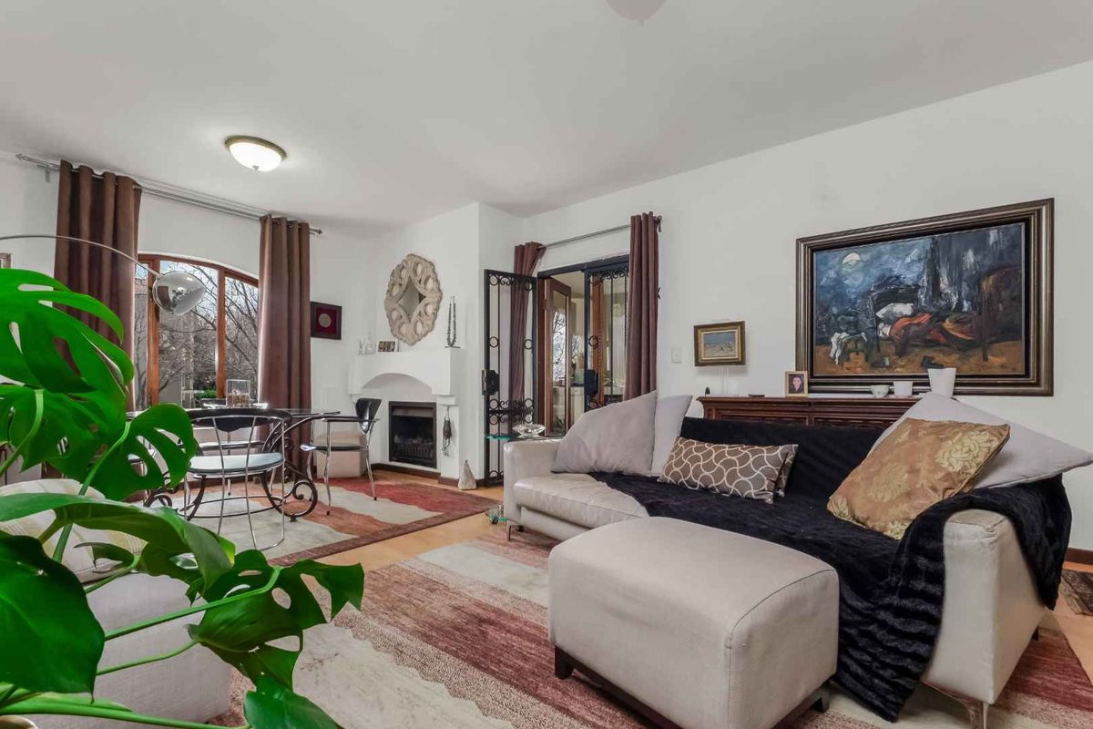 Spacious living room featuring a fireplace, arched window, and access to an outdoor area through security-gated french doors.