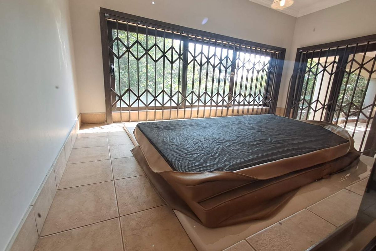 A bedroom featuring tiled flooring, large windows with integrated security gates, and recessed ceiling lighting.
