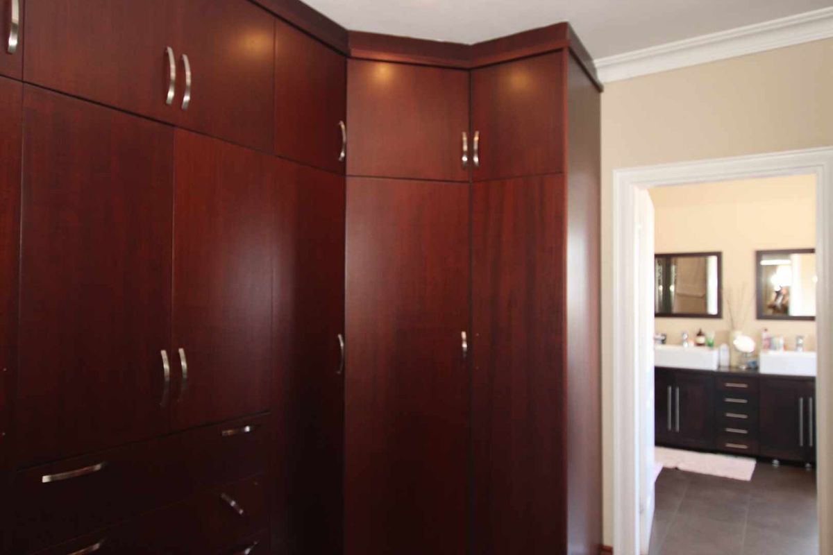 A bedroom featuring extensive floor-to-ceiling dark wood built-in cabinetry with a doorway leading into an adjoining bathroom.