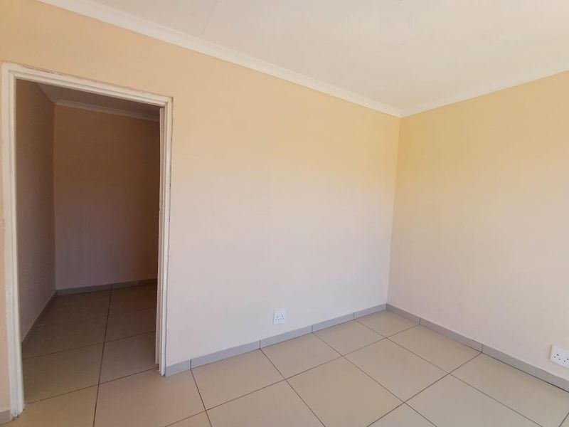 A clean, empty bedroom featuring neutral wall paint, tiled flooring, and standard electrical fixtures, providing a blank canvas for personalization.