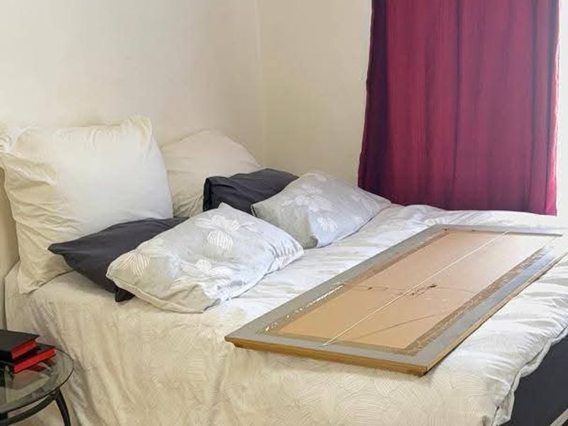 A functional bedroom featuring tiled flooring and a window with a curtain rod.