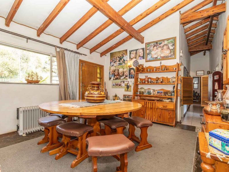 Dining area featuring exposed timber ceiling beams, tiled flooring, and natural light through a large window.