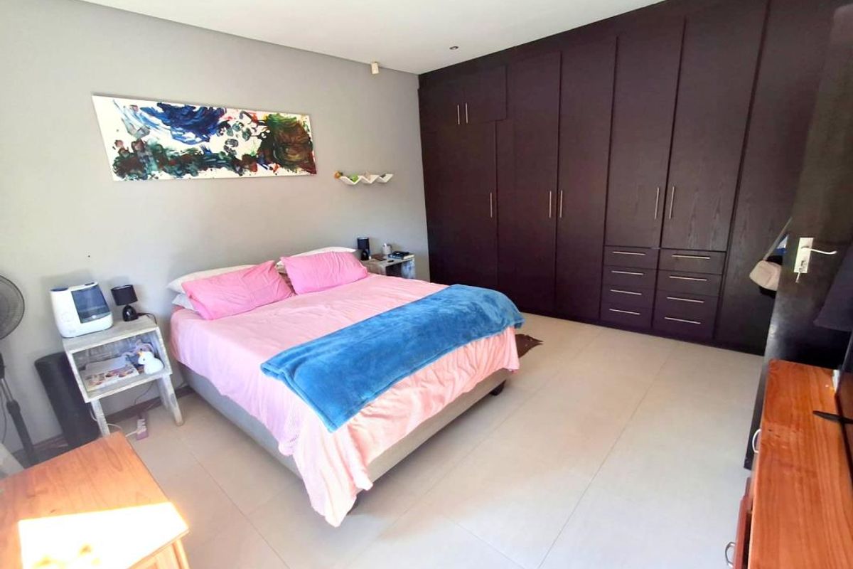 Spacious bedroom featuring extensive dark wood built-in cupboards and neutral tiled flooring, offering ample storage and a clean, functional layout.
