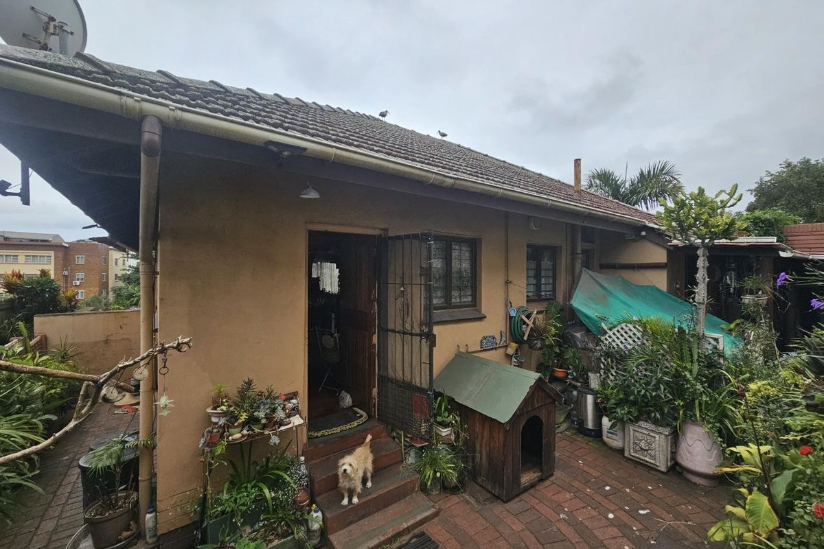 Rear exterior view of the property featuring a tiled roof, brick paved patio area, and direct access to the interior.