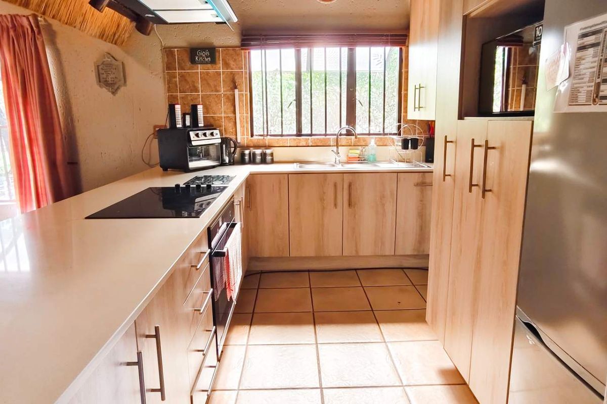 A functional kitchen featuring light wood cabinetry, tiled flooring, a built-in hob, and an integrated oven, offering a practical workspace.