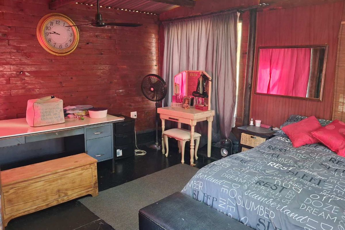 A rustic bedroom featuring timber wall cladding and a corrugated iron ceiling, offering a unique cabin-style aesthetic.