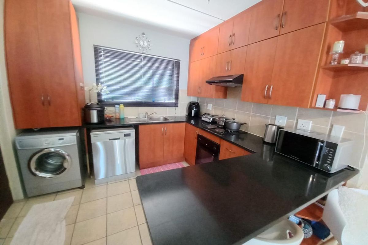 Functional kitchen featuring wood-finish cabinetry, granite countertops, integrated appliances, and tiled flooring, offering a practical layout for daily meal preparation.