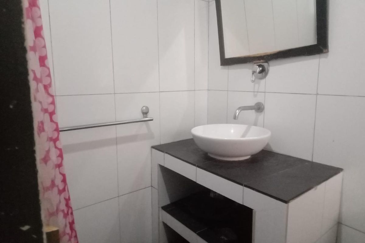 A compact bathroom featuring a modern vessel sink set on a tiled vanity, wall-mounted faucet, and full-height wall tiling.