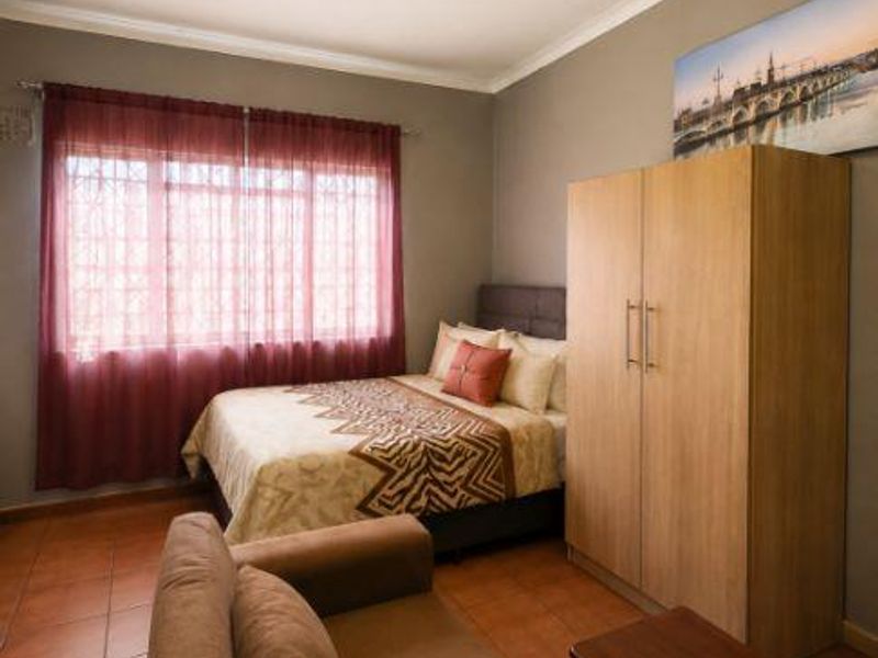 A bedroom featuring tiled flooring and a window fitted with security bars.