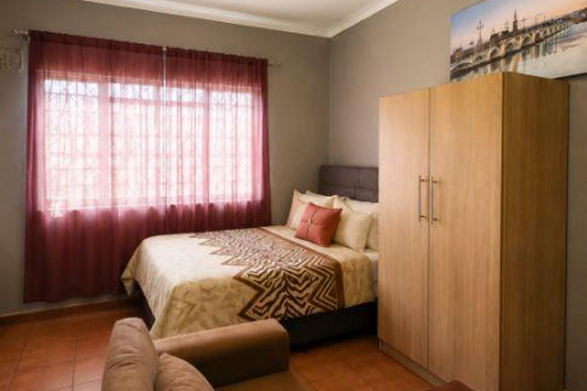 A bedroom featuring tiled flooring and a window fitted with security bars.