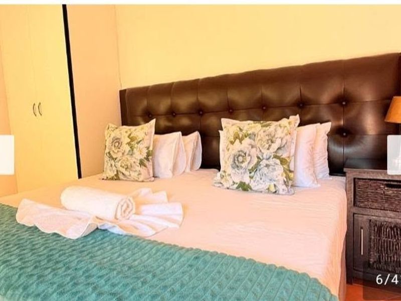 A bedroom featuring built-in cupboards and a large tufted headboard.