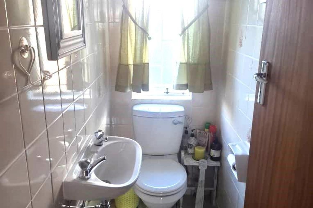 A compact guest bathroom featuring a wall-mounted basin, a standard toilet, and tiled walls.