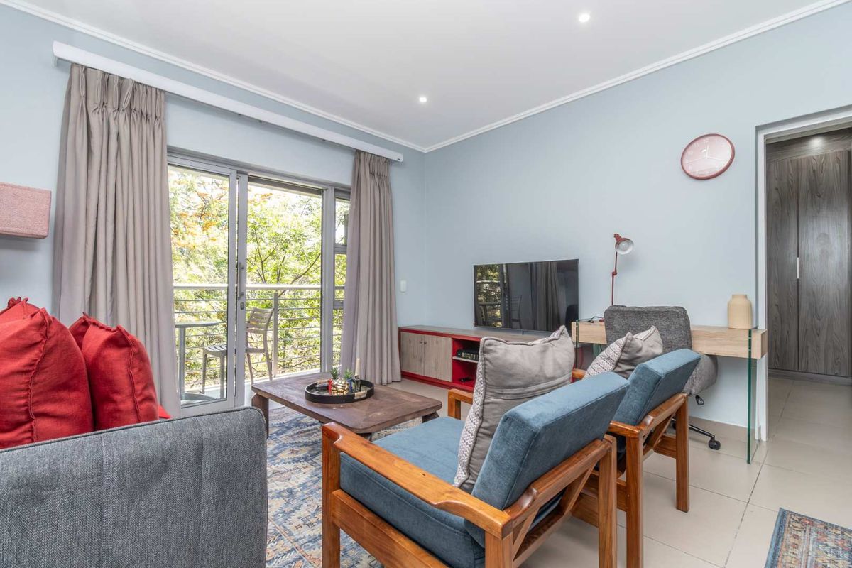 A bright and well-maintained living room featuring tiled floors, recessed lighting, and a sliding glass door providing access to a private balcony.