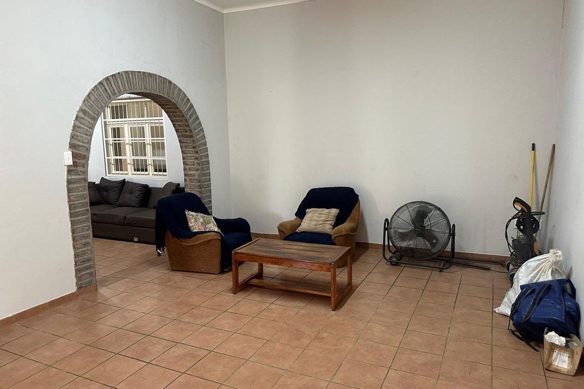 A living area featuring terracotta floor tiles and a distinctive exposed brick archway leading to an adjacent room.